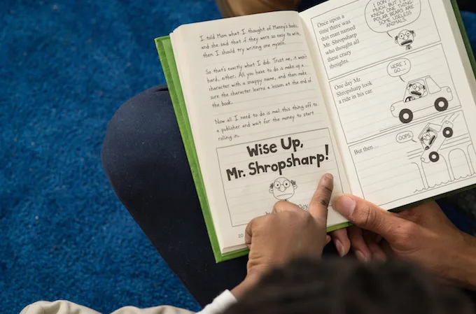 finger pointing at a word in a book