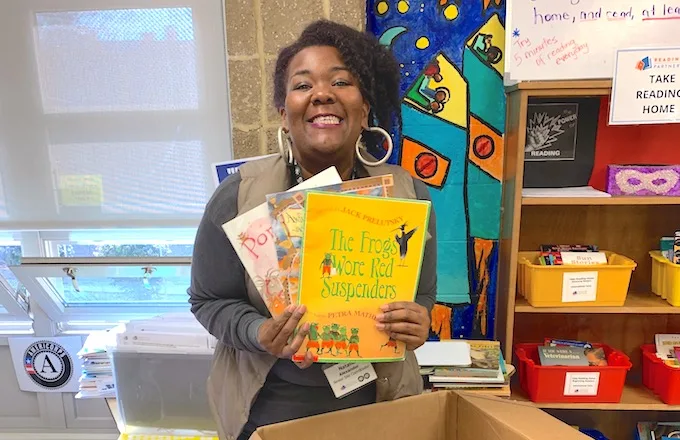 americorps member holding up a few books and smiling