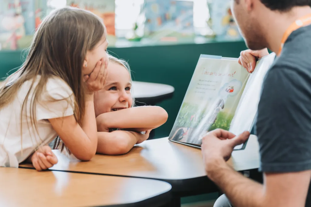 students looking at tutor reading to them in awe and joy