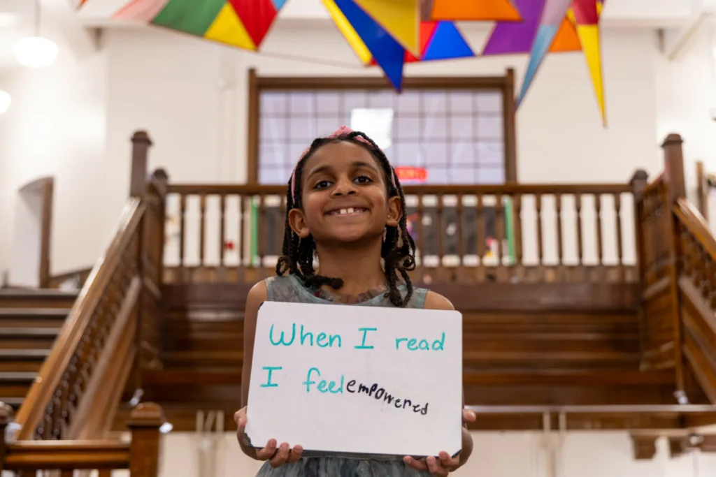 student holding up a sign that says "when I read I feel empowered"