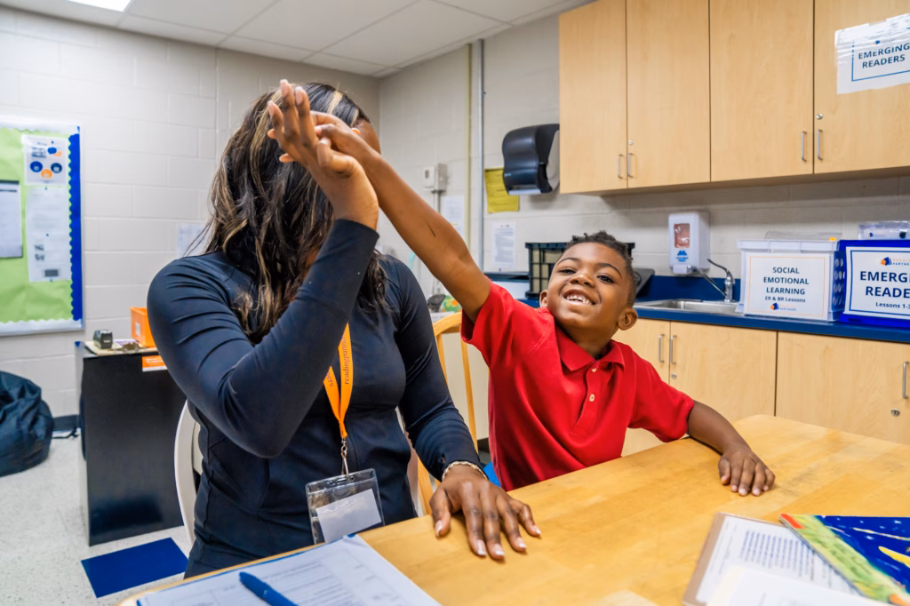 a tutor-student pair high-fiving, proving that reading is a civil right