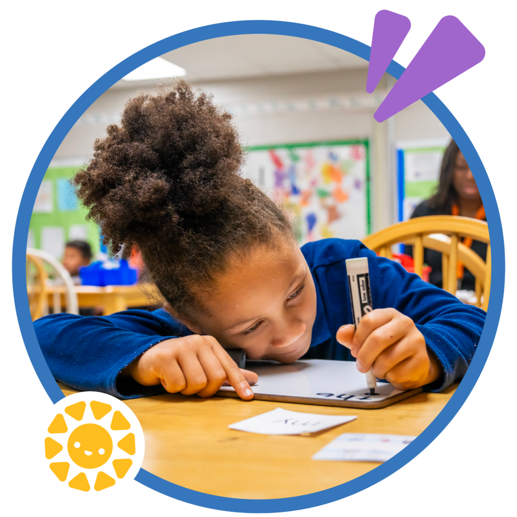 a student writing on a whiteboard as she practices her letters and words