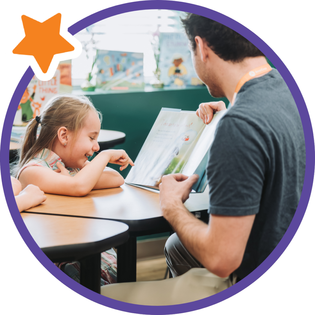 student pointing at book and smiling